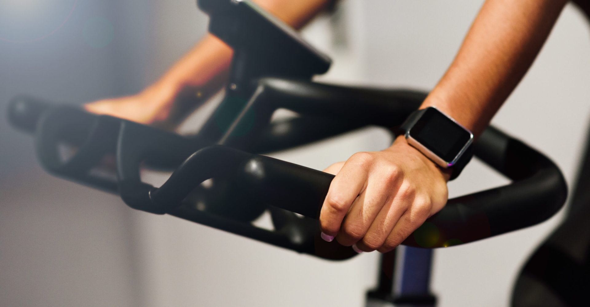 Woman at a gym doing spinning or cyclo indoor with smart watch
