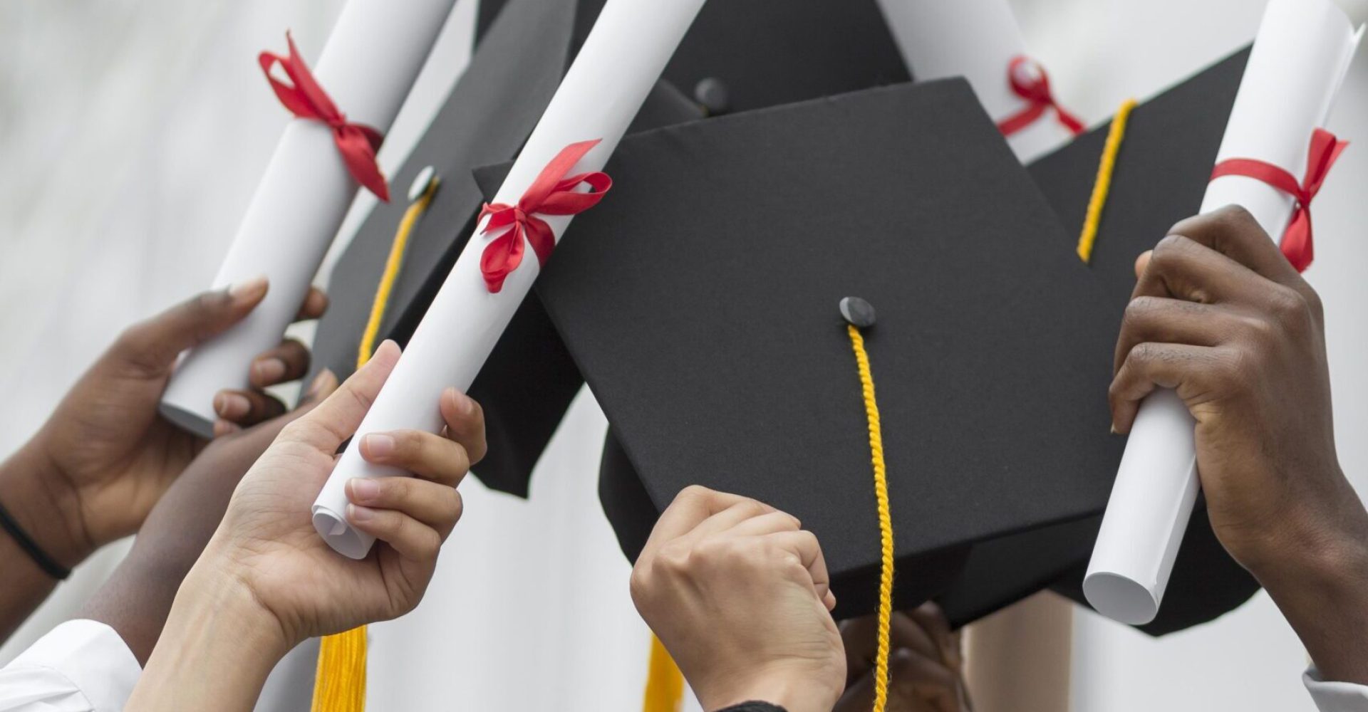 cerrar-manos-sosteniendo-diplomas-y-gorras