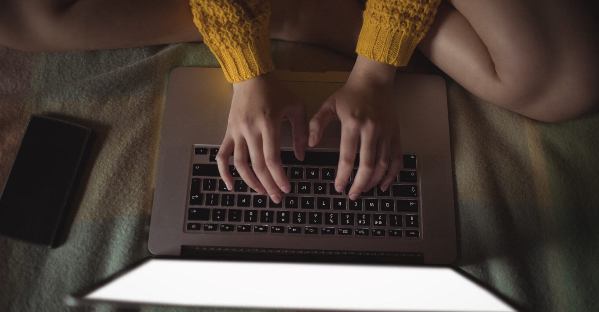 Woman using laptop on bed in bedroom