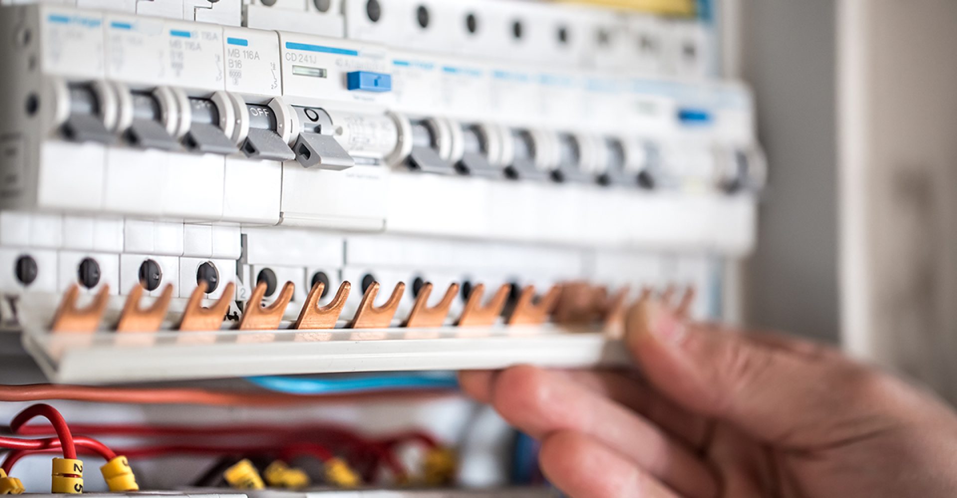 Man, an electrical technician working in a switchboard with fuses. Installation and connection of electrical equipment. Close up.