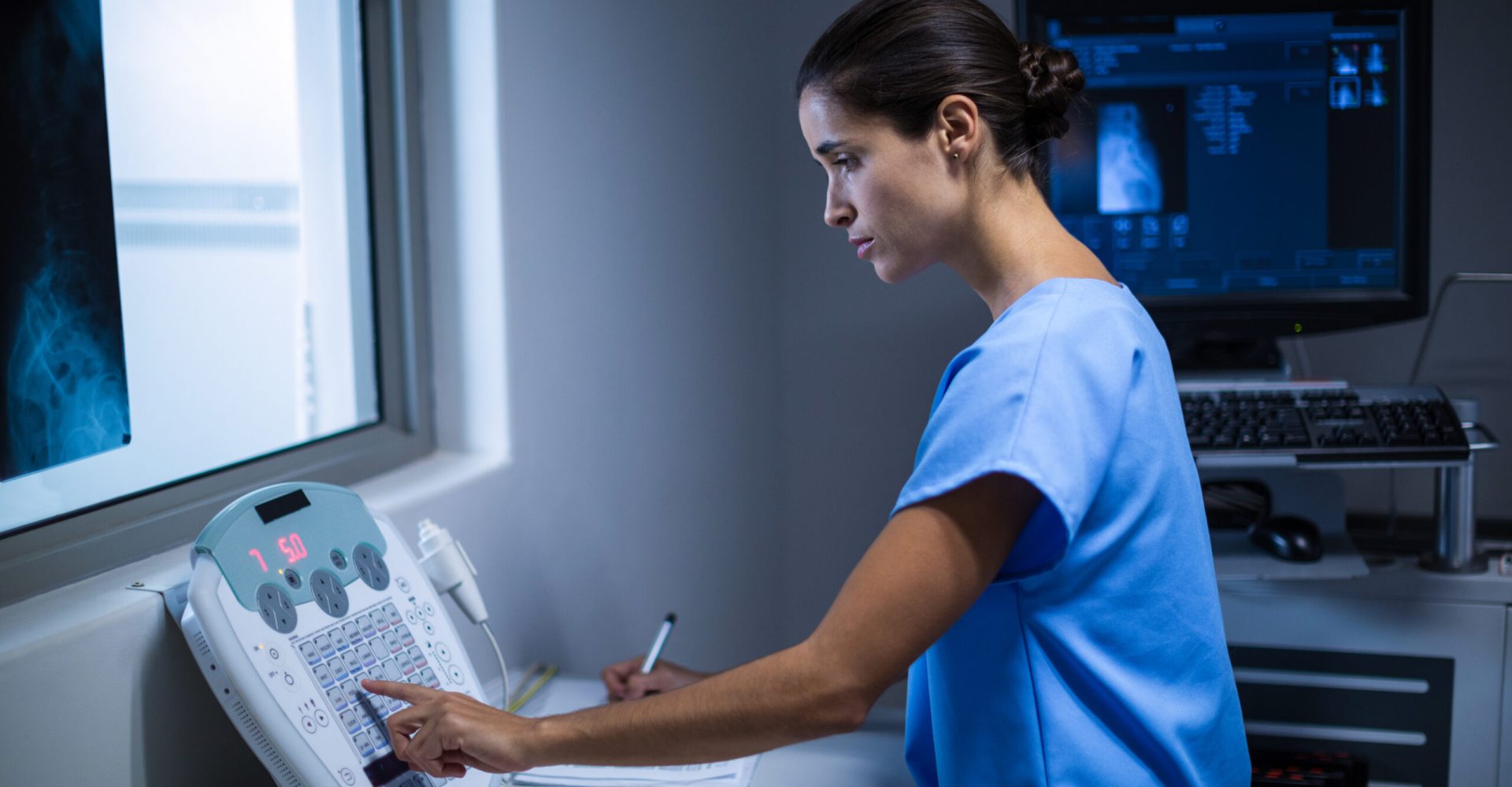 Nurse taking notes in x-ray room at hospital