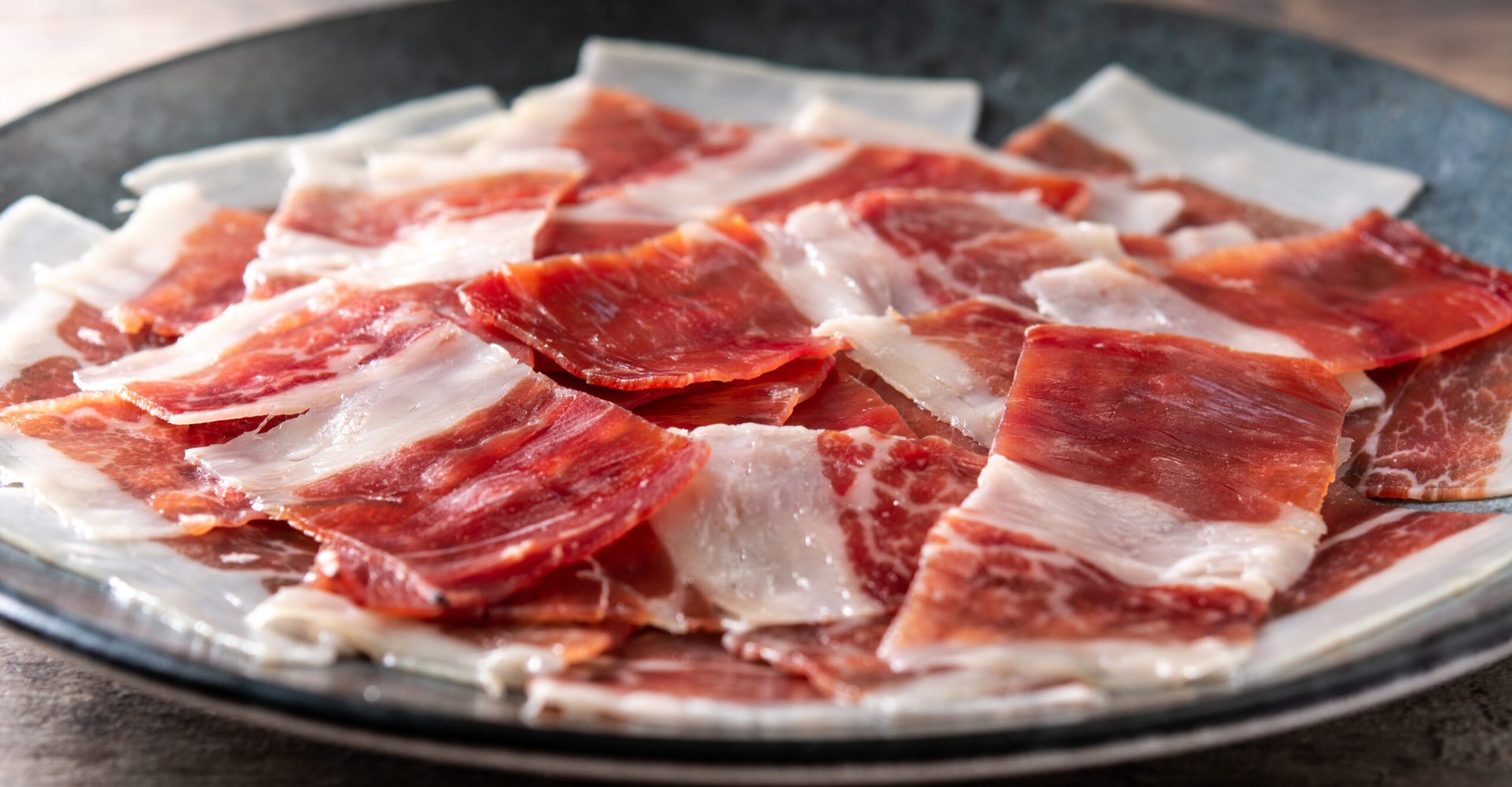 Spanish serrano ham slices on black plate