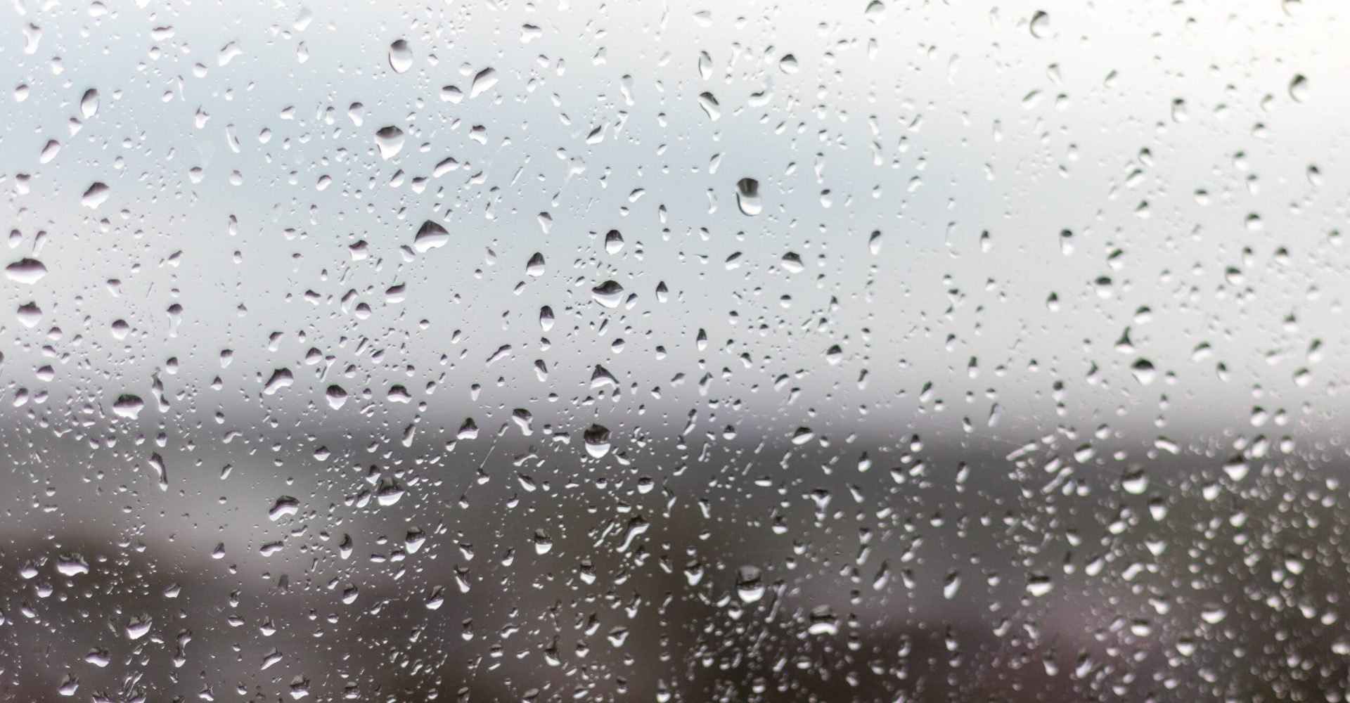 Closeup shot of a window on a rainy day, raindrops rolling down the window