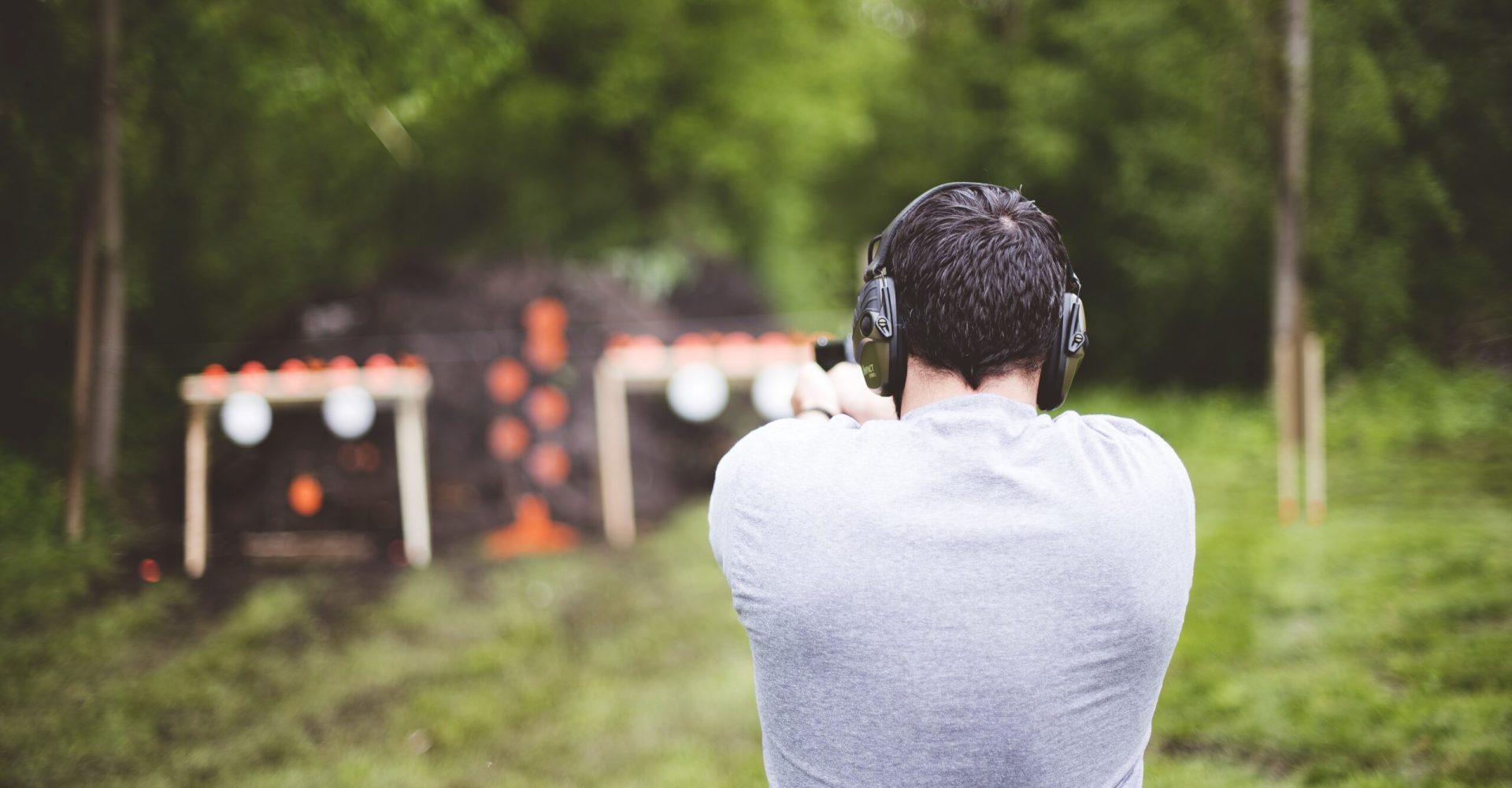 Shallow focus shot from behind of a male shooting a gun at a gun range