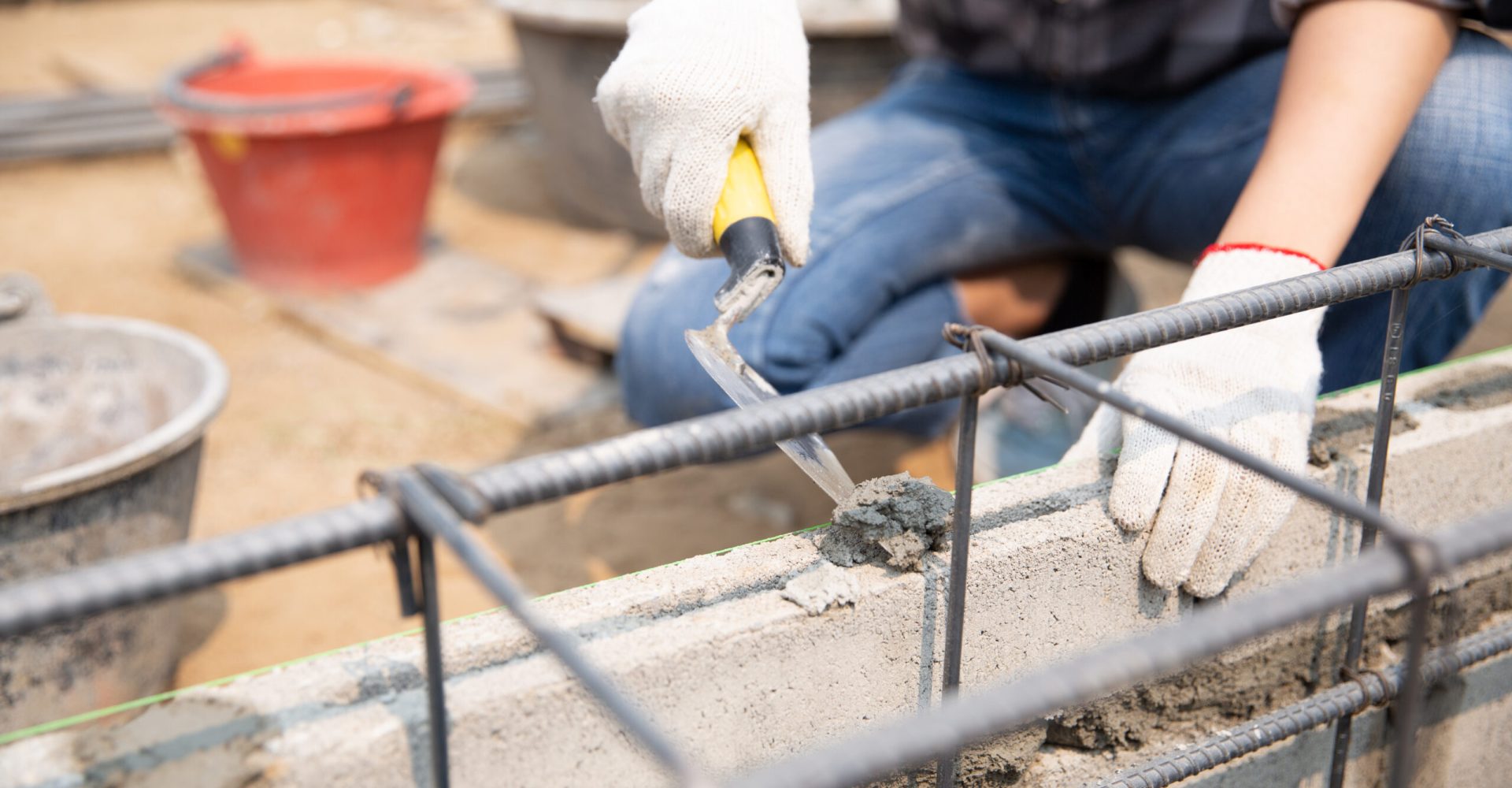 Bricklayer worker installing brick masonry on exterior wall with